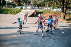 fotografia przedstawia grupę dzieci jeżdżących na rolkach na skateparku. trwają warsztaty.